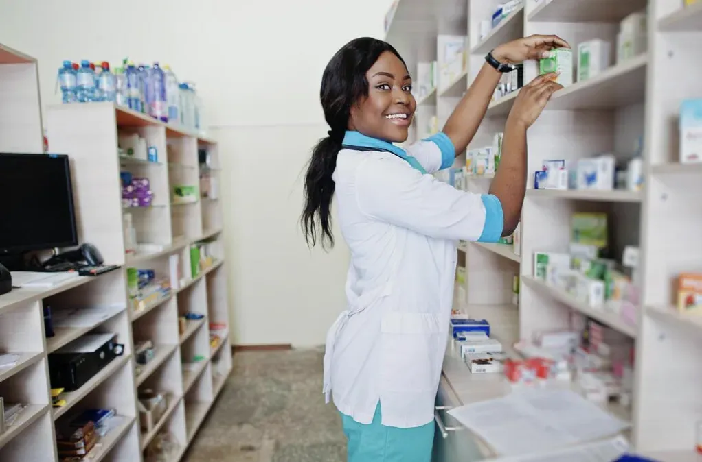 A pharmacist reaching for a box on the shelf